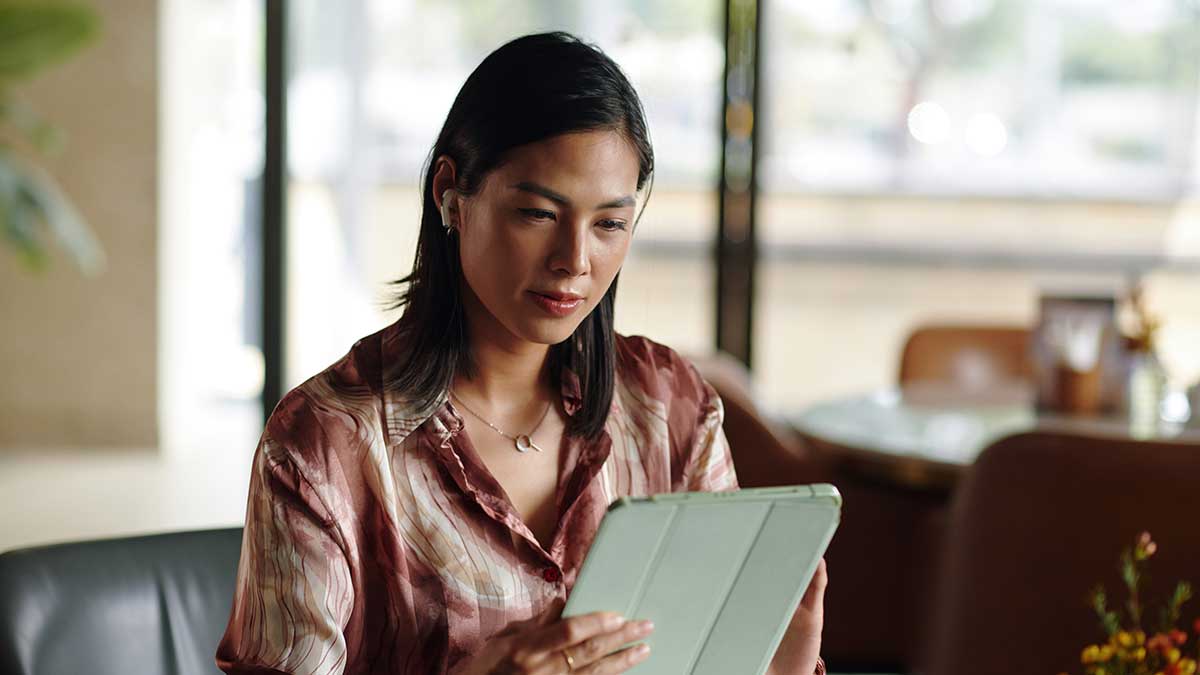 businesswoman sitting cafe table and reading article on tablet computer